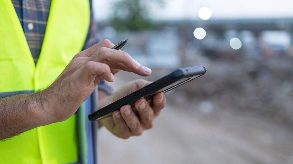 Construction worker using mobile device in field
