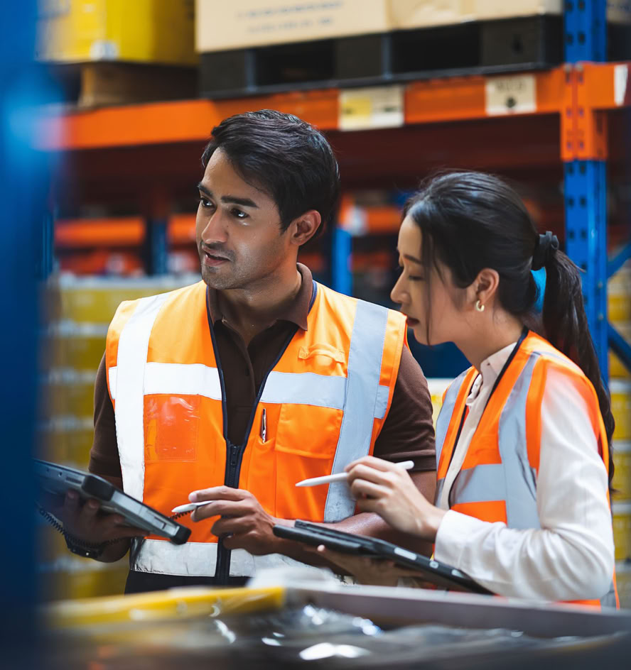 Two warehouse associates reviewing a tablet