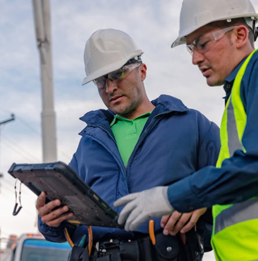 Two utility field workers reviewing a job on a tablet